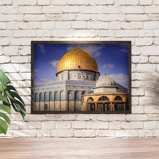 Framed picture of a religious building with a gold dome on a white brick wall.