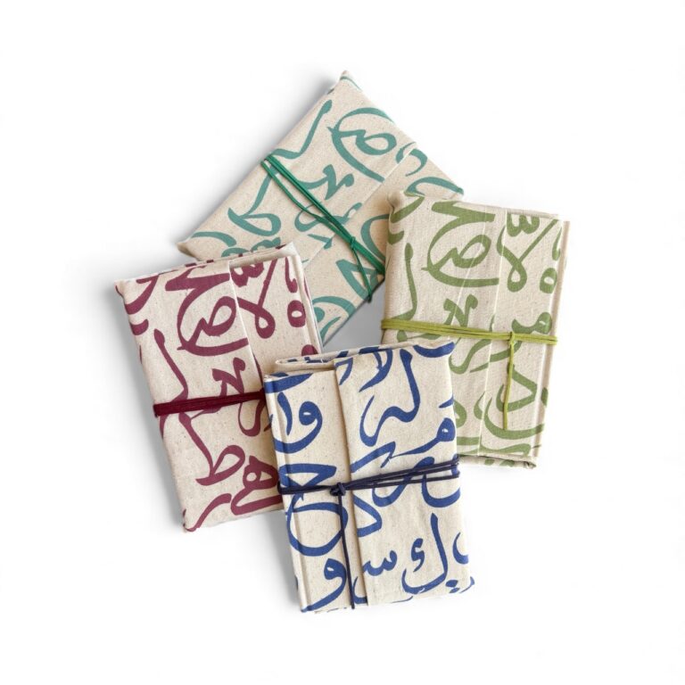 Four folded fabric pieces with colorful Arabic text patterns on a white background