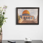 Framed artwork of a architectural landmark on a wall above a desk with a cup and phone.