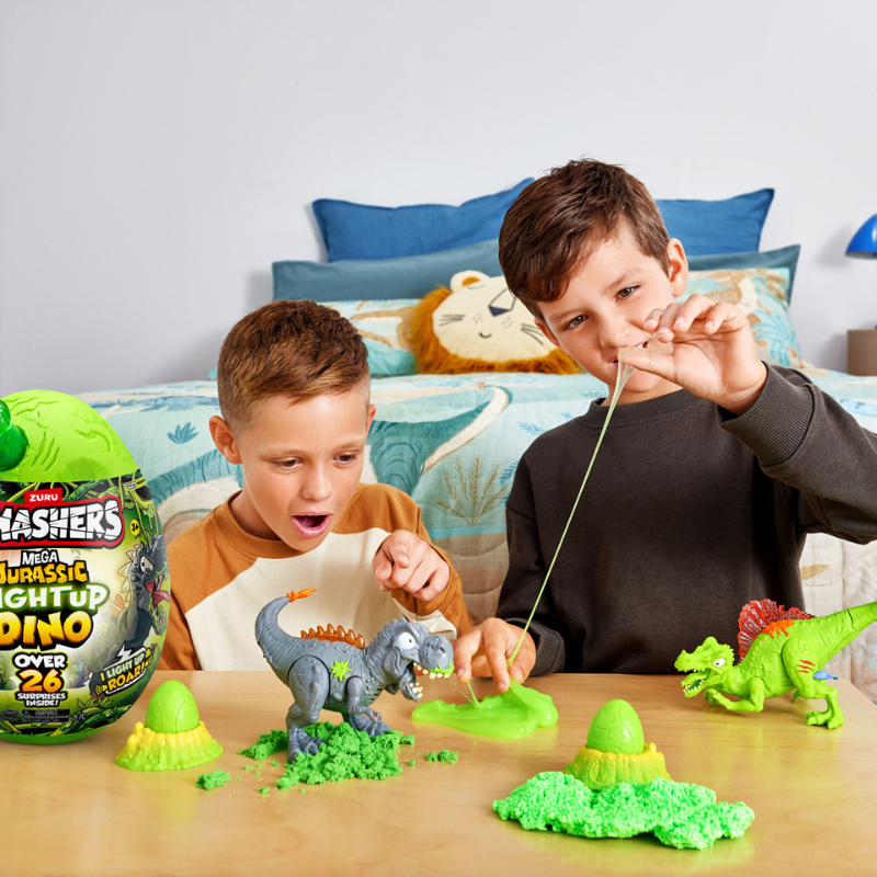 Two children playing with a dinosaur toy set on a table, with a colorful dinosaur pillow in the background.