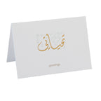 White greeting card with gold Arabic calligraphy and 'greetings' text on a white background